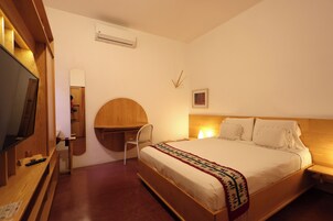 A bedroom with a wooden bed, a desk, a chair, a television, and a mirror.