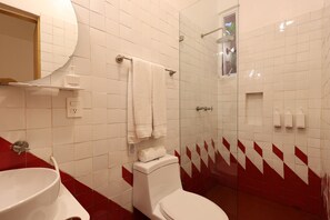 A bathroom with a white sink, toilet, and shower. There are towels hanging on a rack, and a mirror above the sink.
