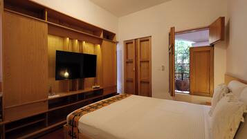 A bedroom with a bed, wooden wardrobe, TV, and a window with a view.