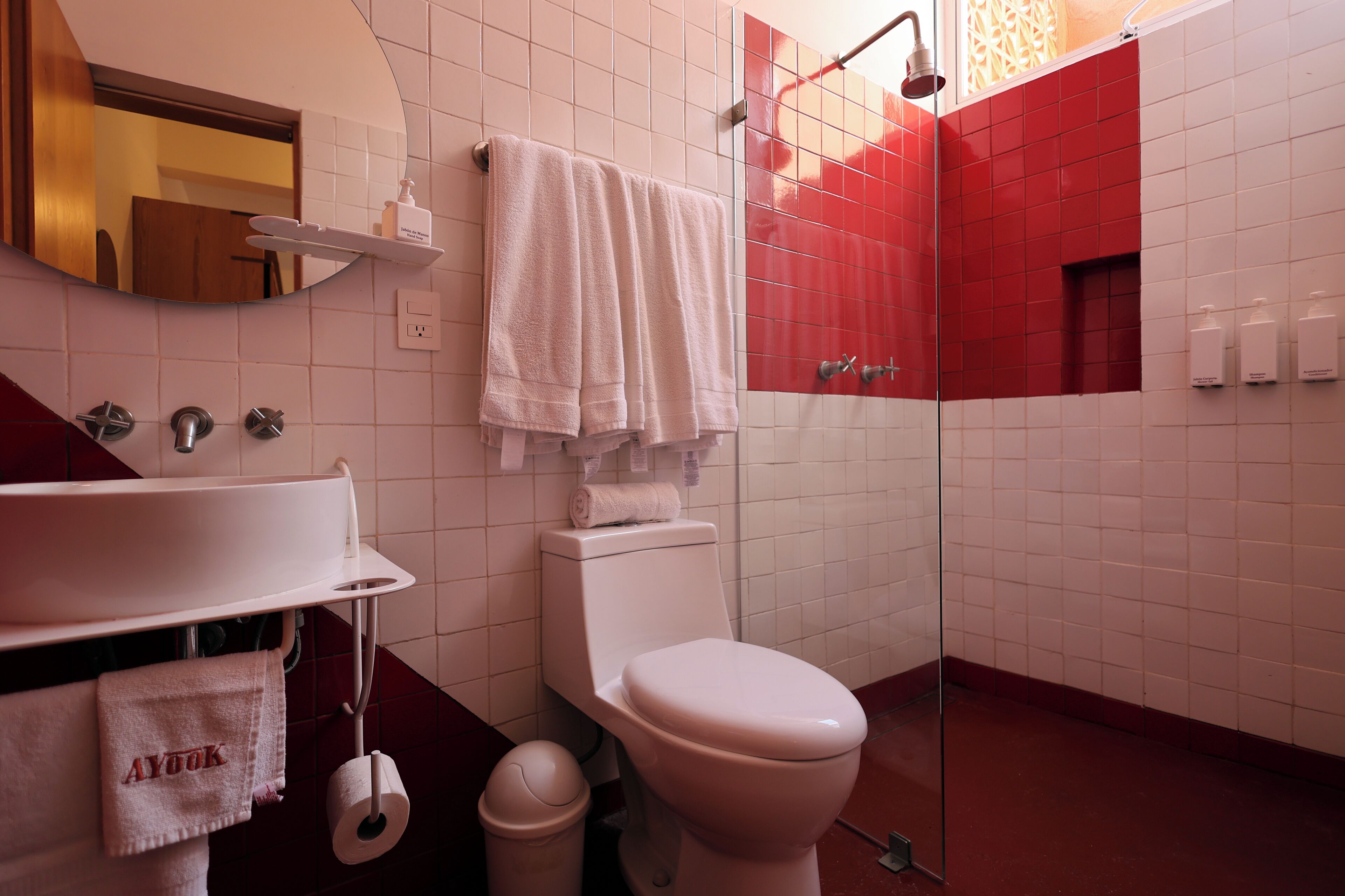 A bathroom with a white sink, toilet, and shower. There are towels hanging on the wall and a mirror above the sink.