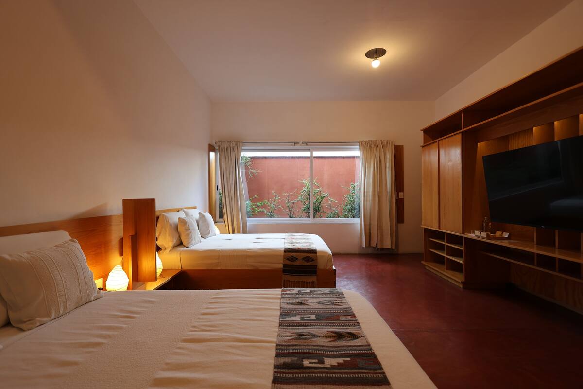 A hotel room with a large bed, a TV, and a window with curtains.