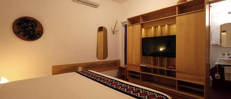 Un dormitorio con cama, televisor, armario y baño.