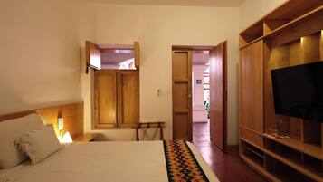 A bedroom with a bed, wooden wardrobe, and a television.