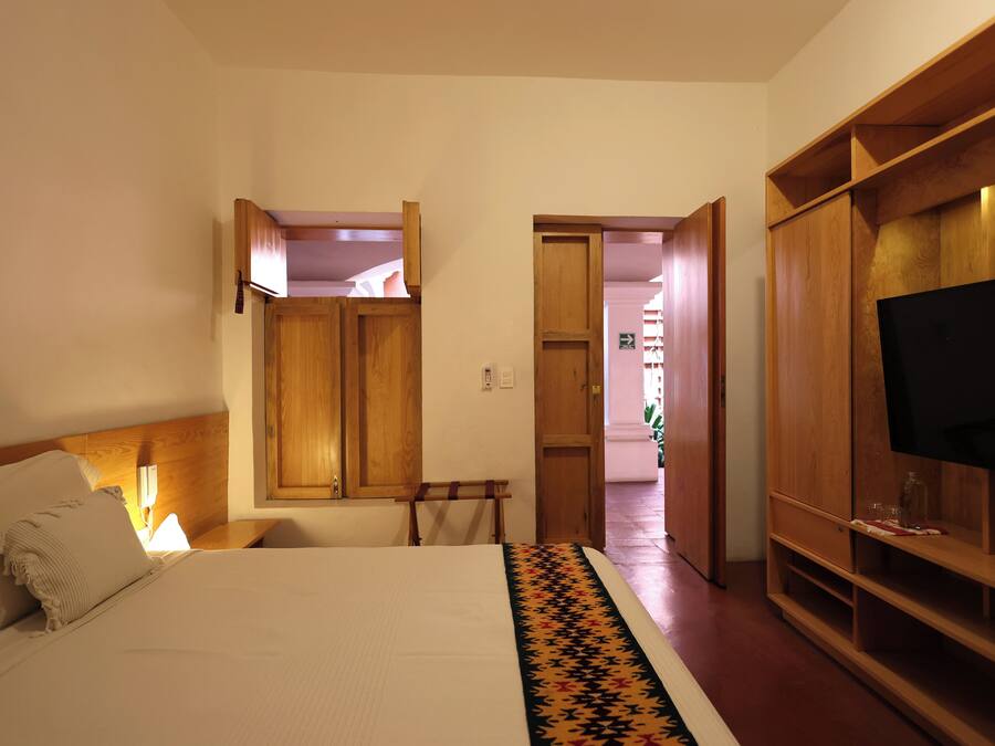 A bedroom with a bed, wooden wardrobe, and a television.