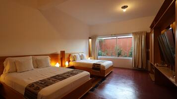 Una habitación de hotel con dos camas, un ventanal con cortinas y suelo de madera.