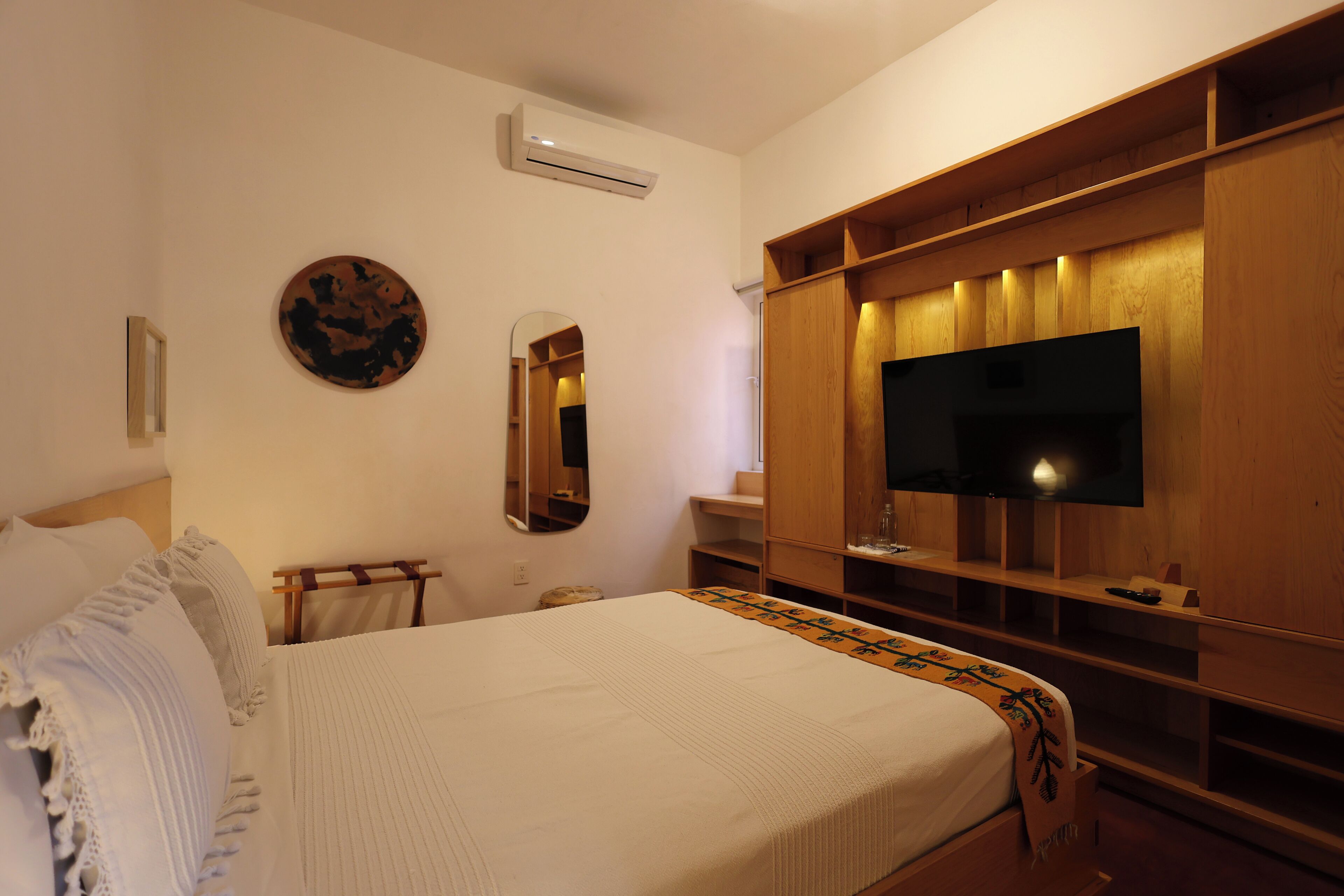 A bedroom with a bed, a TV, a mirror, and a wardrobe.