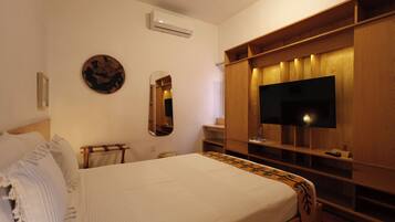 A bedroom with a bed, a TV, a mirror, and a wardrobe.