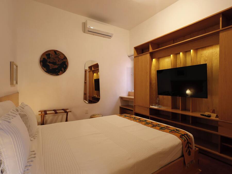 A bedroom with a bed, a TV, a mirror, and a wardrobe.