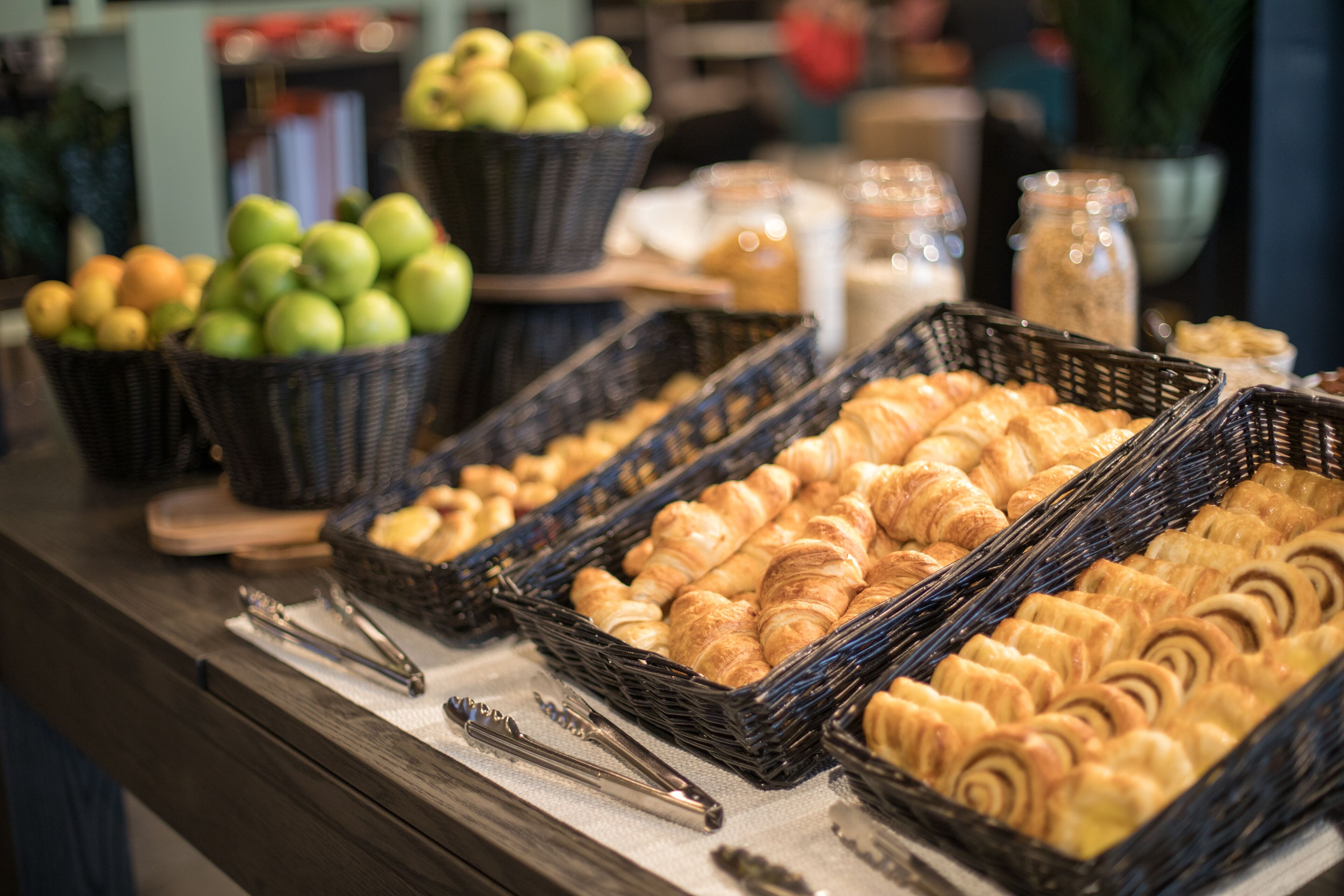 A bakery display with baskets of apples and croissants.