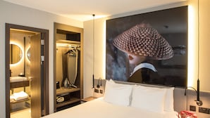 Ein Hotelzimmer mit einem Bett, einem großen Spiegel, einem Kleiderschrank und einem an der Wand befestigten Kunstwerk.