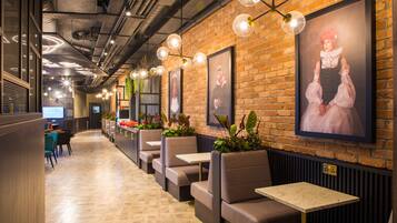 A restaurant with brick walls, framed portraits, and hanging plants.