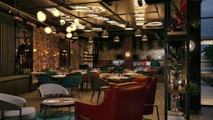 Ein Restaurant mit Backsteinwand, hängenden Pendelleuchten und einer Sitzgegend mit Tischen und Stühlen.