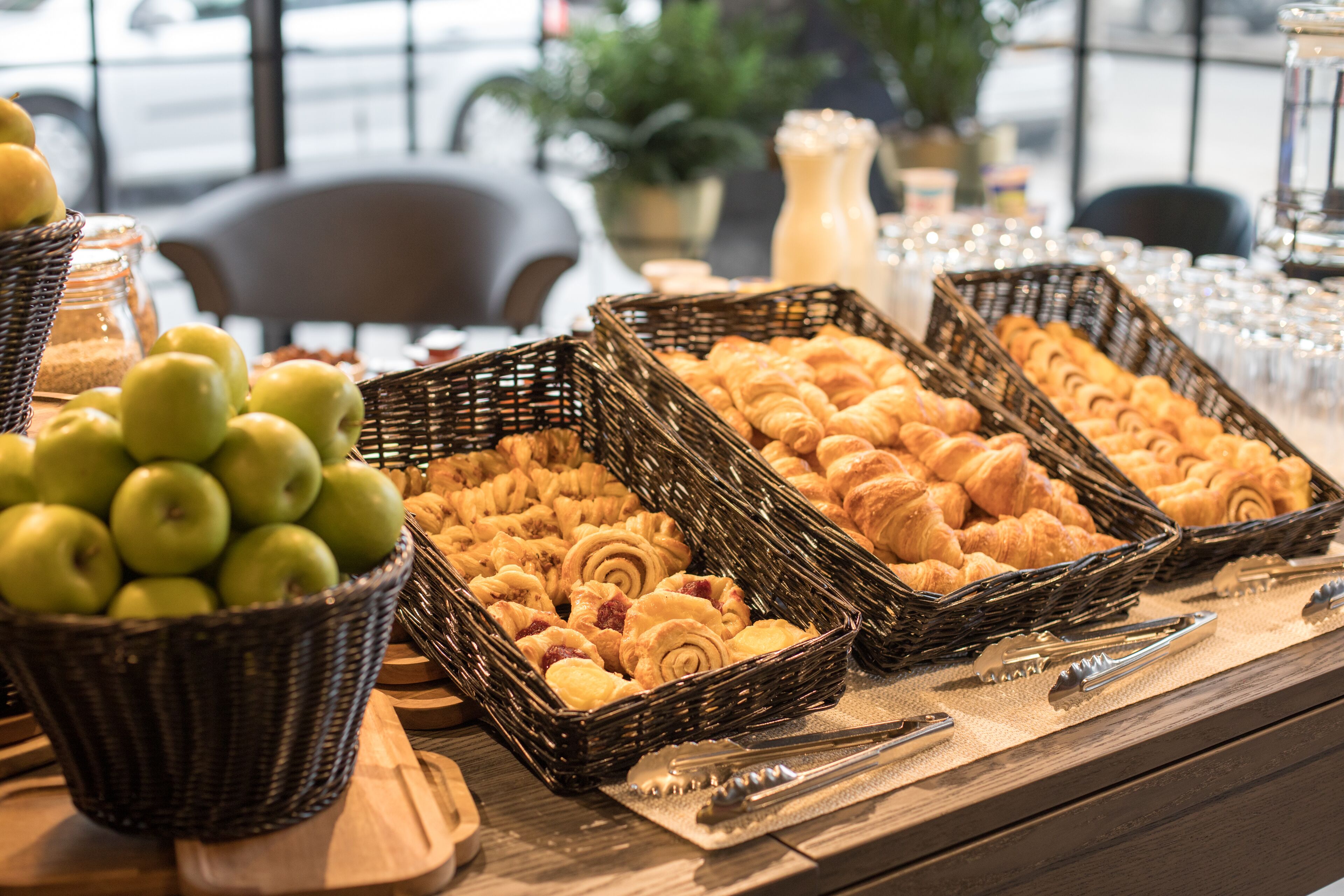A buffet table with baskets of apples and pastries.
