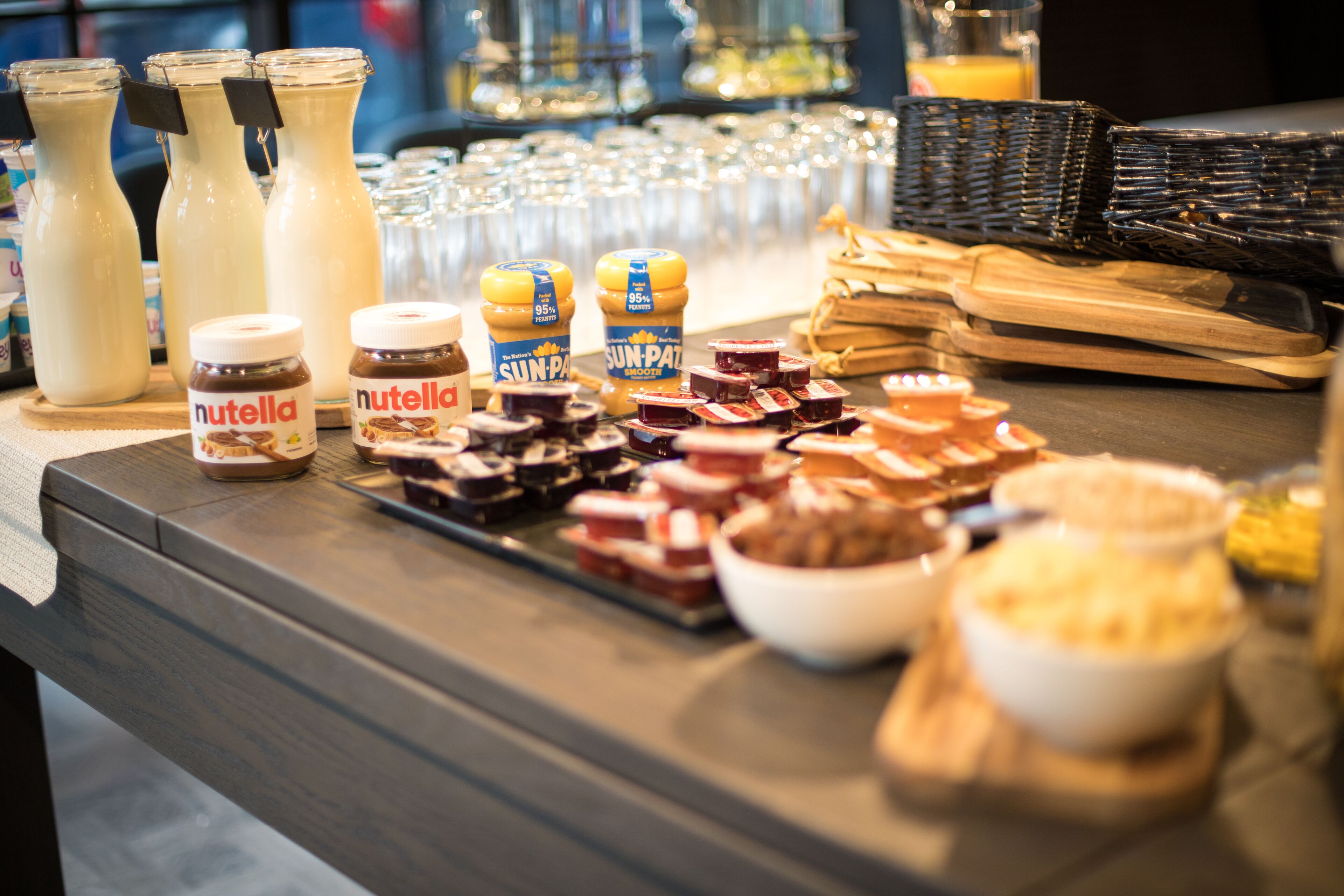 A buffet table with various food items and condiments, including jars of Nutella and Sun-Pa.