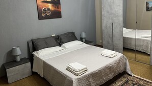 A bedroom with a bed, a nightstand, a lamp, a mirror, and a painting on the wall. - Villa Alladin (Sciacca)