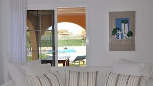 A bedroom with a bed, a window with a view of a swimming pool, and a framed picture on the wall. - ECO Villa Nazaret with Solar Energy (Antigua)