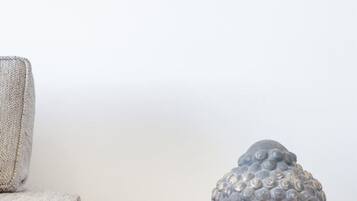 Una escultura de cabeza de Buda sobre una mesa de madera frente a una pared lisa.