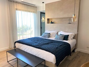 Une chambre à coucher moderne avec un grand lit, des tables de chevet et un banc.