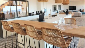 Una cocina moderna con una isla central, taburetes de bar y lámparas colgantes.