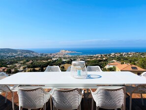 Un espace repas avec une table et des chaises donnant sur une vue sur la côte.