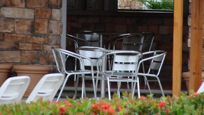 A patio area with a thatched roof, stone wall, metal chairs, and a potted plant. - La Mansión del Faro (Tecolutla)