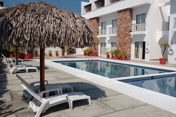 Una piscina al aire libre, sillones reclinables de piscina