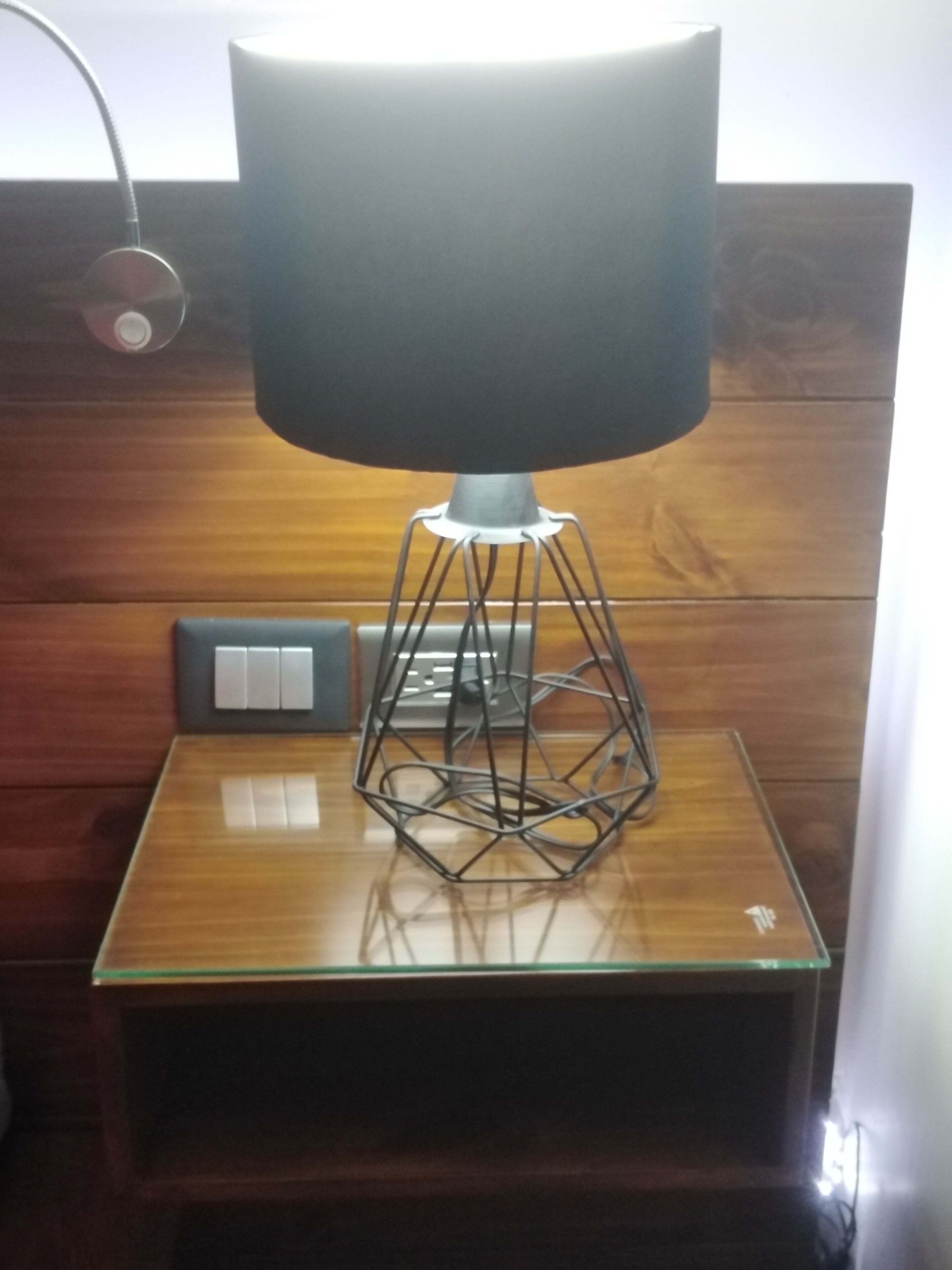 Une lampe moderne, dotée d’un pied aux formes géométriques, posée sur une table en bois.