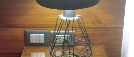 Una lámpara moderna con base geométrica sobre una mesa de madera.