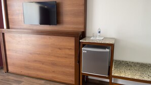 A wooden cabinet with a flat-screen TV mounted above it, a small refrigerator on a wooden stand, and a water bottle on a marble countertop. - La Mansión del Faro (Tecolutla)