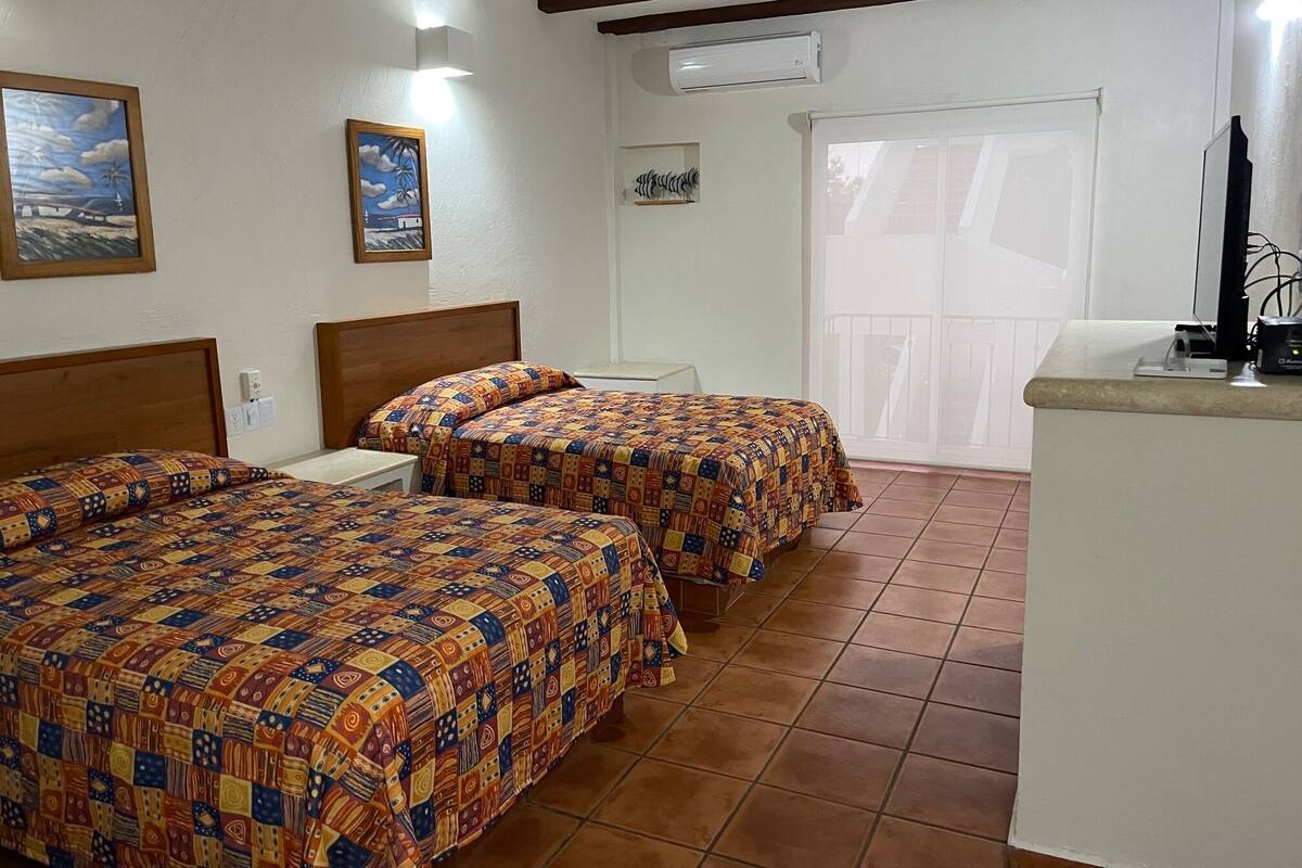 A room with two beds, a small table, a TV, and a window with a view.