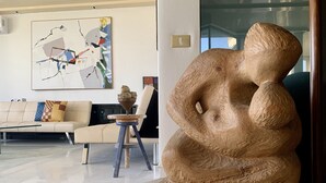 A modern living room with a beige sofa, a coffee table, and a wooden sculpture.