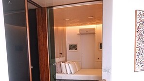 A modern interior with a wooden sculpture, a bed, and a framed picture on the wall.