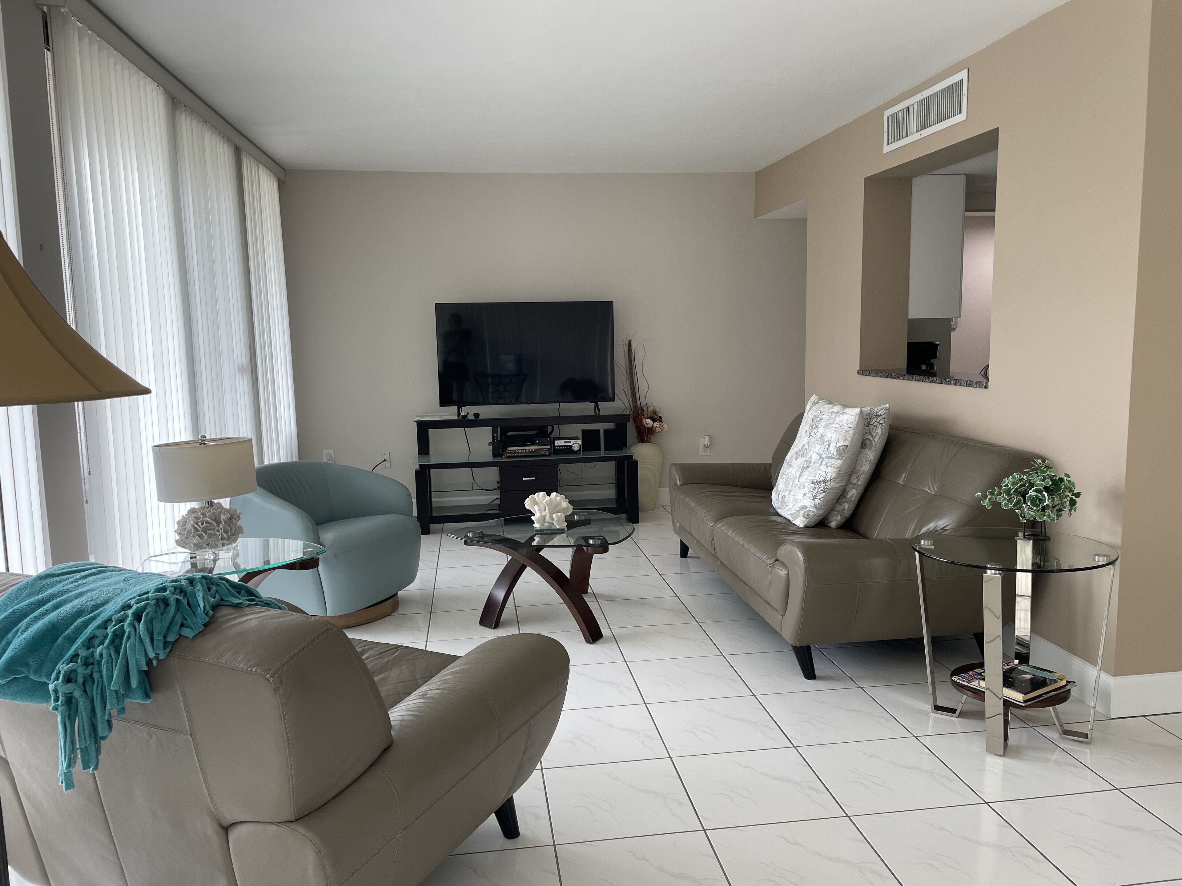 Un salon moderne avec un canapé, un fauteuil et une table basse en verre.