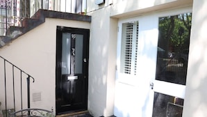 A black door with the number 93, a white door with a window, and a metal staircase leading to an upper level. - 2-Bed, Sleeps 4, Garden (London)