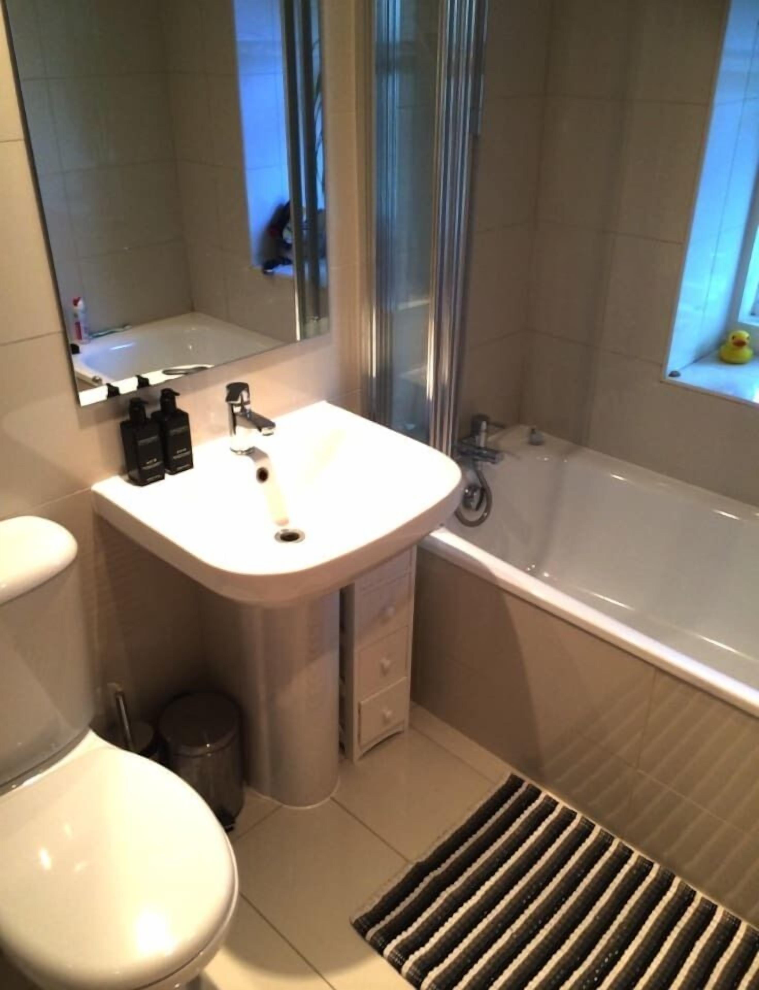 A modern bathroom with a white sink, mirror, and toilet.