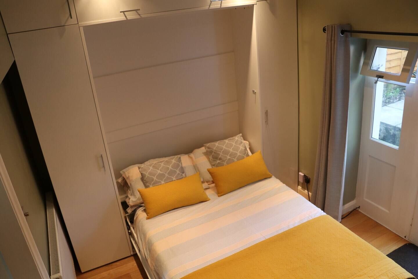A bedroom with a bed, pillows, a wardrobe, and a window.