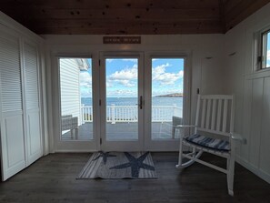Een houten interieur met uitzicht op zee door een glazen deur.