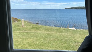 A view of a lake with boats, a grassy area, and a forested island. - Spectacular views, close to down town Rockland (Owls Head)
