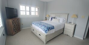 Una camera da letto con un letto, una TV su un mobile in legno, una finestra e lampade da comodino.