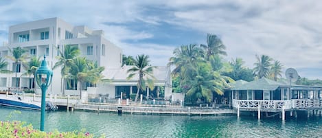 A waterfront hotel with a modern white building, a dock with a boat, and a covered area with a railing.