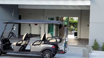 Ein Golfmobil steht vor einem Gebäude mit einer Rezeption und einer grünen Tür.