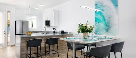 Una cocina moderna con una isla central, taburetes de bar y un ventanal grande.