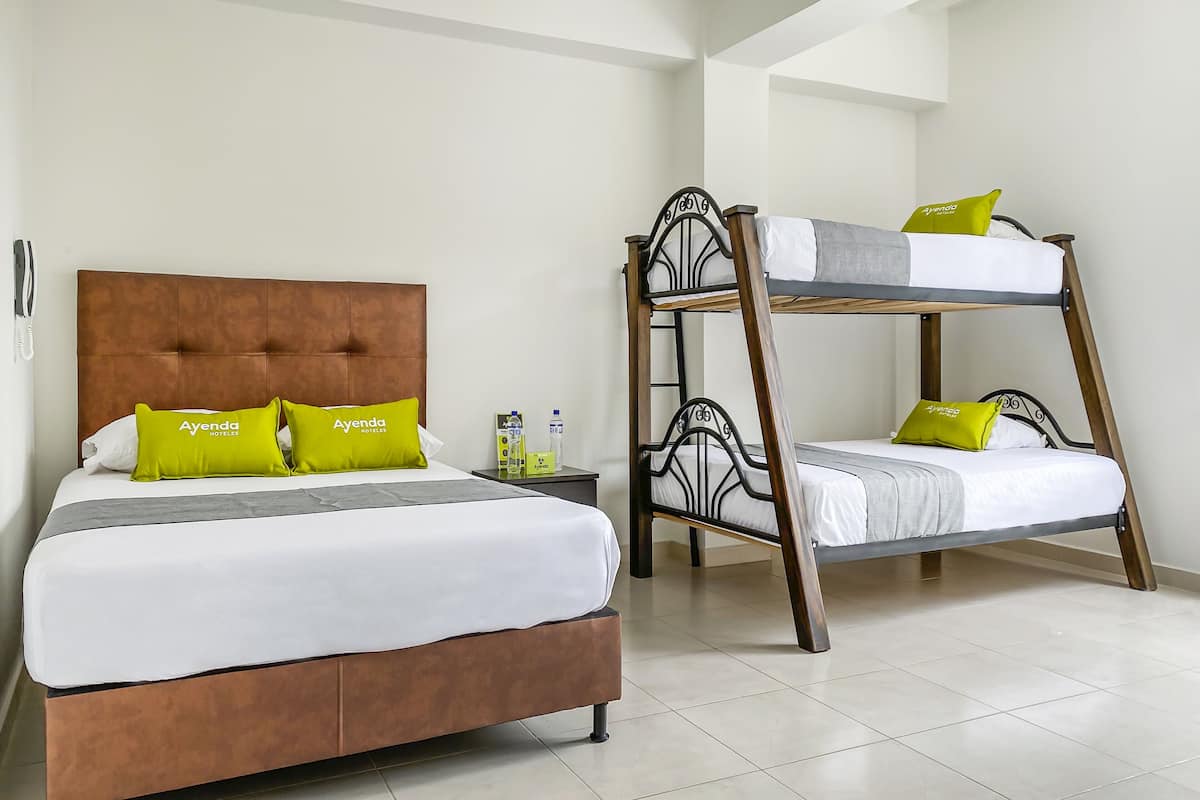 Ein Hotelzimmer mit einem großen Bett, einem kleineren Stockbett und einem Nachttisch mit Pflegeprodukten.