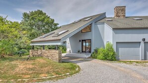Uma casa moderna de dois andares com base de pedra, varanda coberta e garagem.