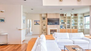 Uma sala de estar moderna com um sofá branco, mesa de centro de madeira e prateleiras embutidas.