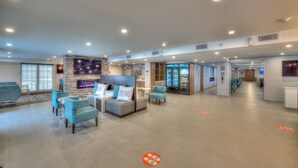 Un hall d’entrée spacieux avec des coins salon, une cheminée et un grand écran de télévision.