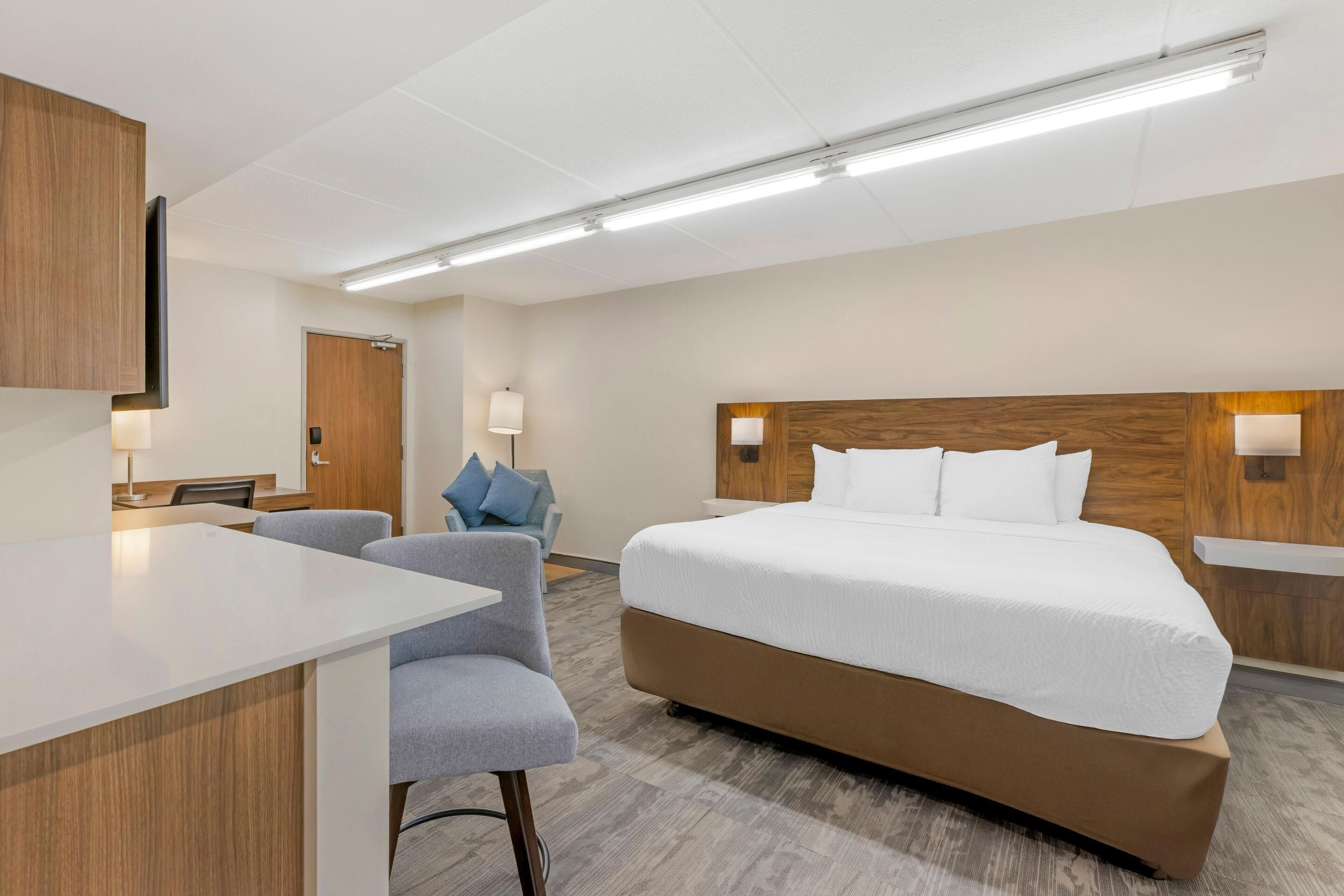 Una camera d'albergo moderna con un letto grande, una scrivania, una sedia e un piccolo divano.