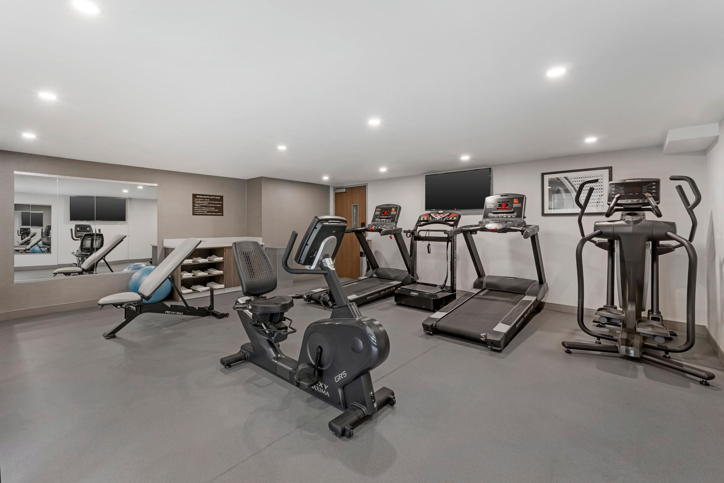 A gym with various exercise equipment including treadmills, an elliptical, and a stationary bike.