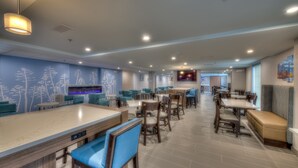 Un restaurant spacieux avec de hauts plafonds, un éclairage encastré et différents types de sièges, notamment des tables, des banquettes et des places au bar.