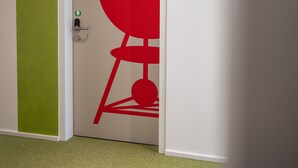 Una puerta con una reja roja y una franja vertical verde en la pared de la izquierda.